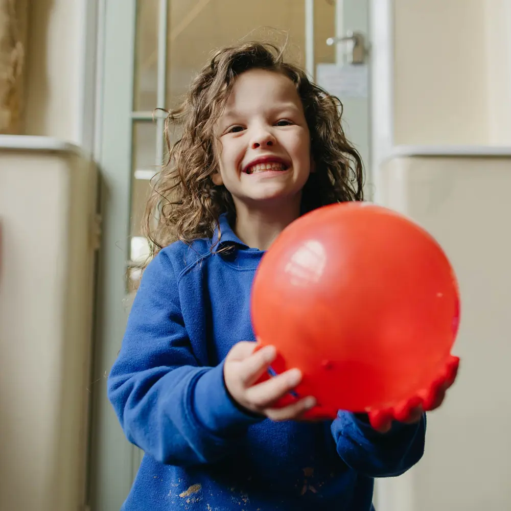 A young girl at Westmorland School holding a red ball