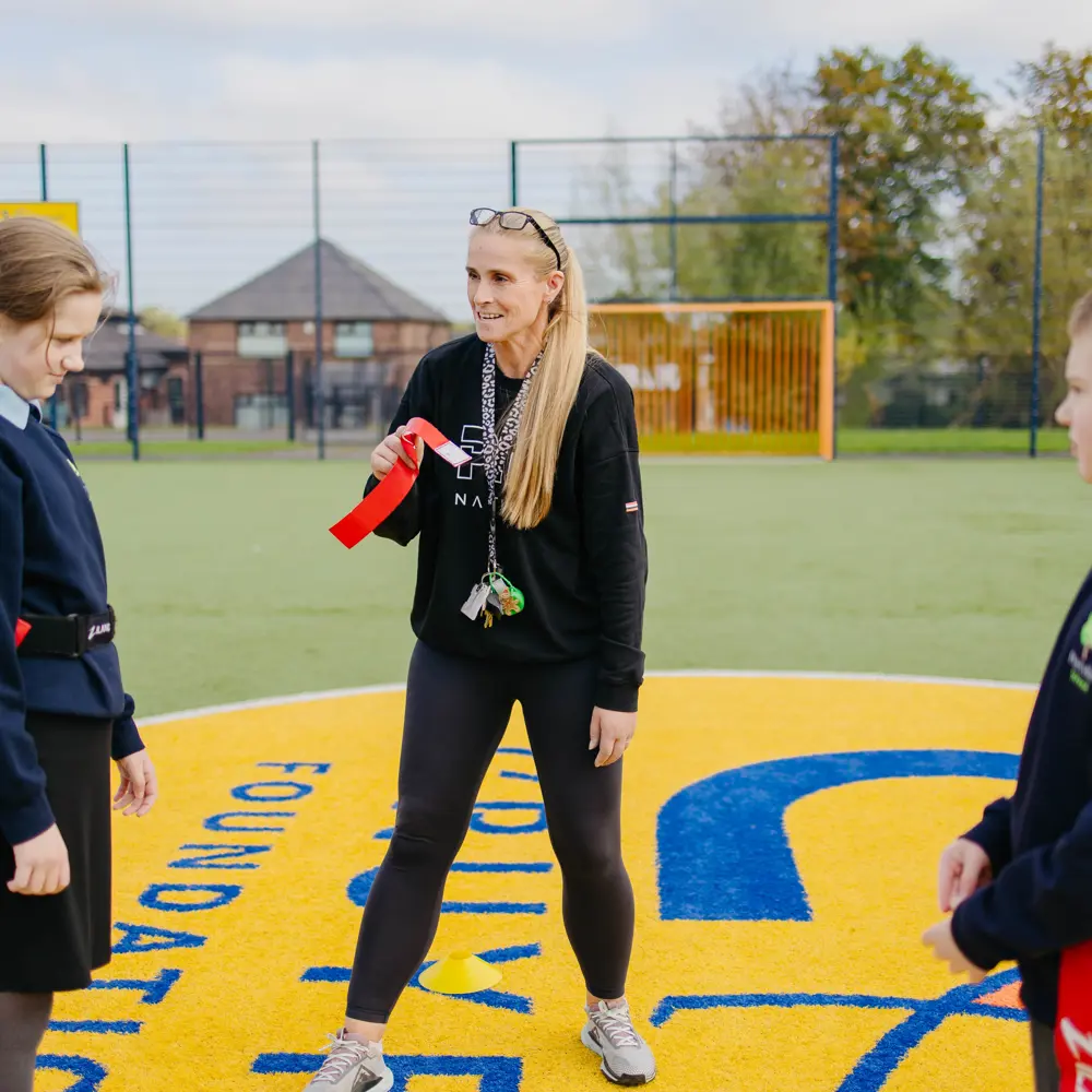 Two pupils on the court yard with a member of staff during PE