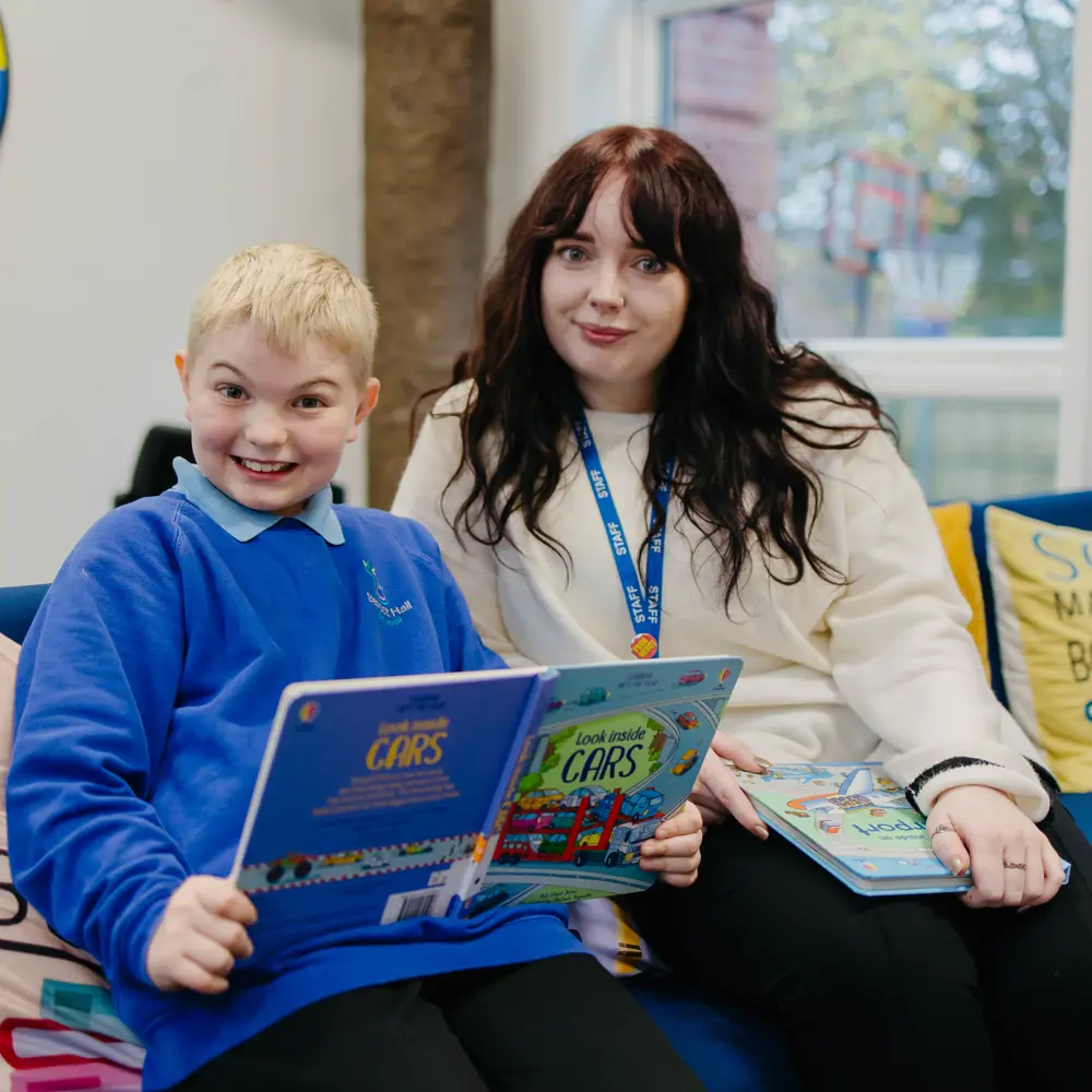 Young pupil and female member of staff at Bescot Hall School reading in the library