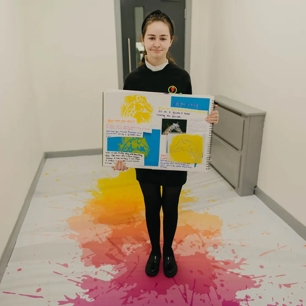 Young girl showing her classwork in a corridor at Ashbrooke School