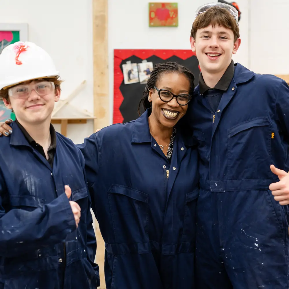 Two pupils from Avon Park School with a staff member, smiling, wearing overalls