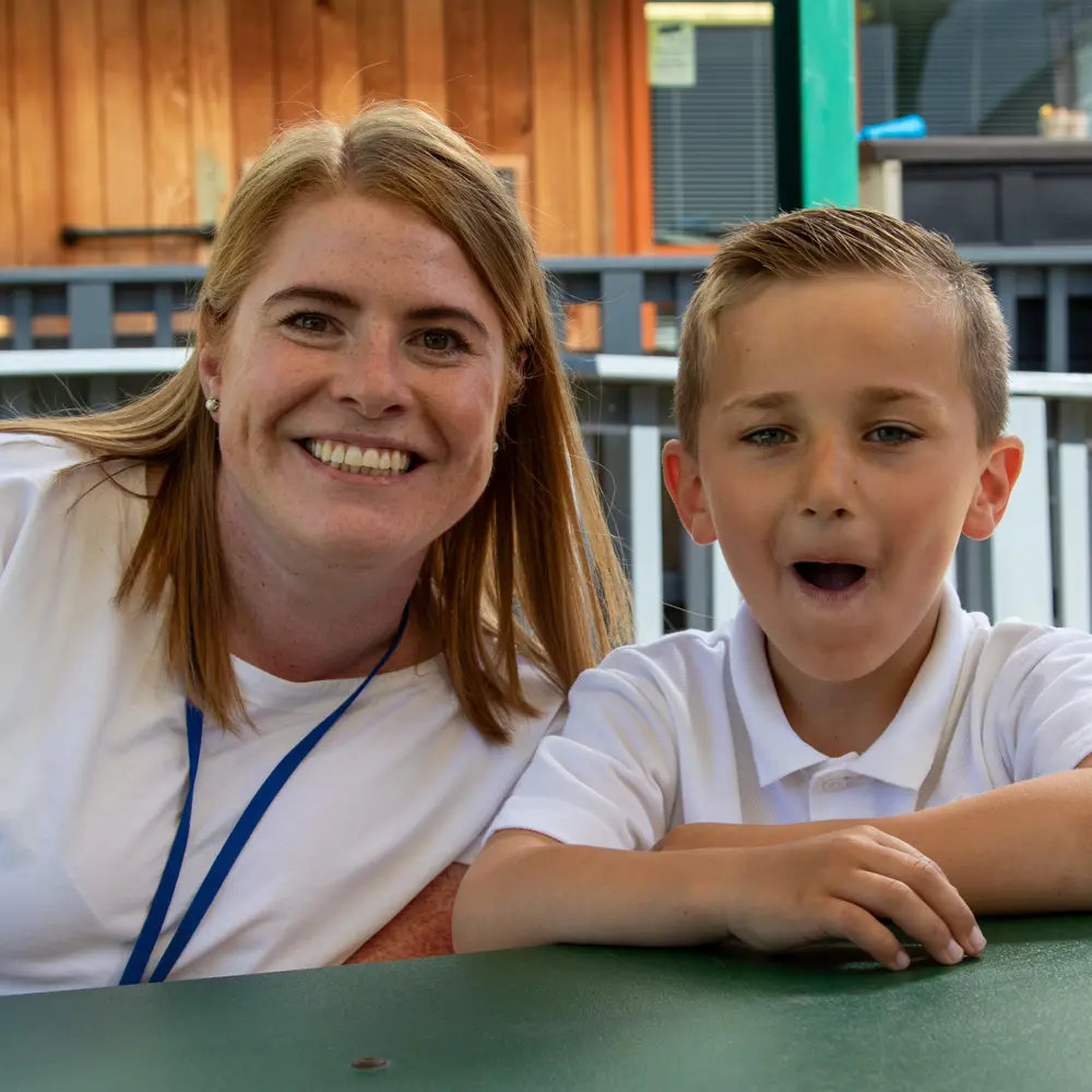 Young boy from lakeside School sat with a teacher on a bench outside