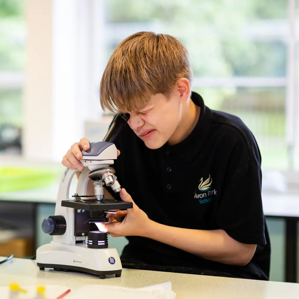 Young boy looking into a microscope in the lab at Avon Park School