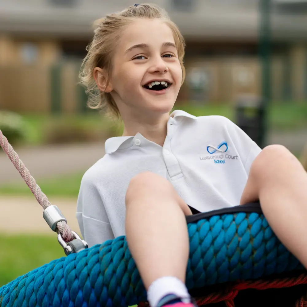 A blond haired girl from Luxborough Court School on a basket swing