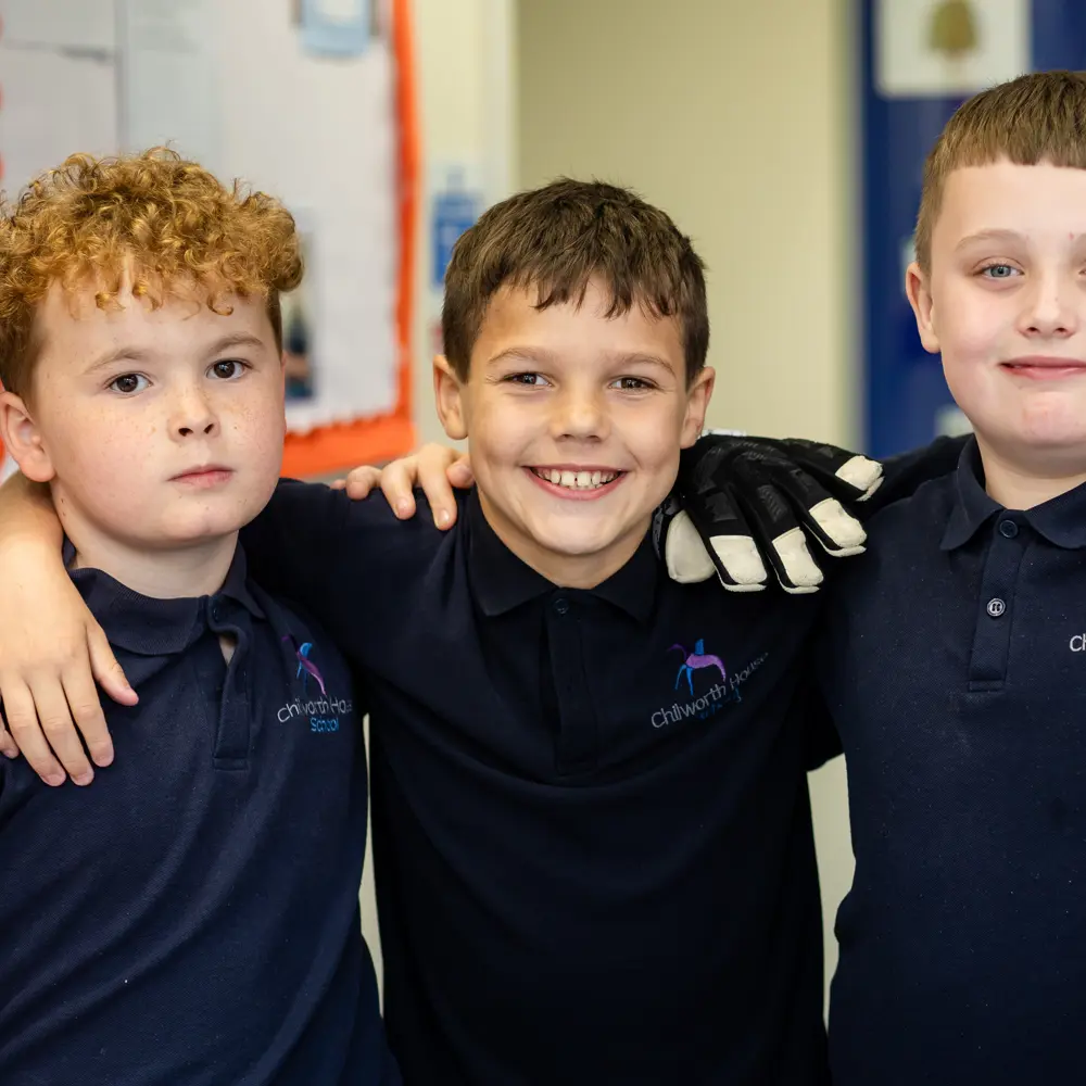 4 boys from Chilworth house School with their arms on each others shoulder smiling into the camera