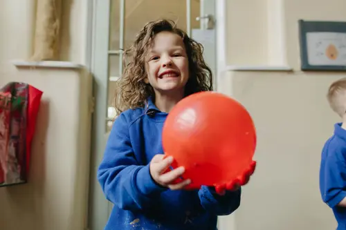 Young girl from Westmorland School holding a red balloon