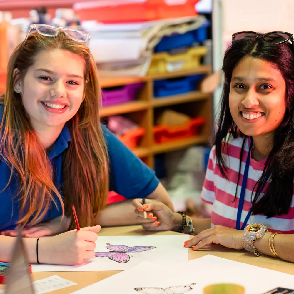 A young girl from Chilworth House Upper colouring with a member of staff