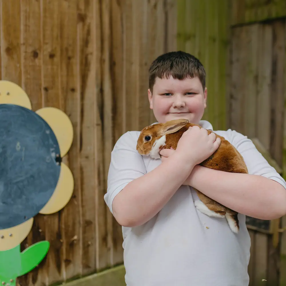 A young boy holding a brown rabbit from Hall Cliffe Primary School