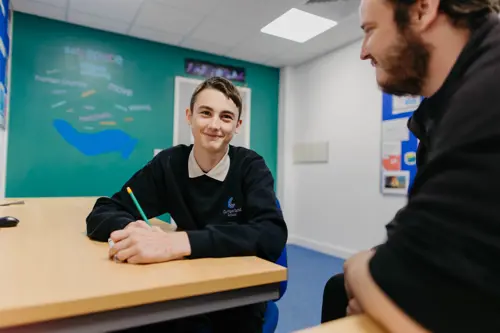 A young boy with brown hair at Cumberland School smiling at a staff member