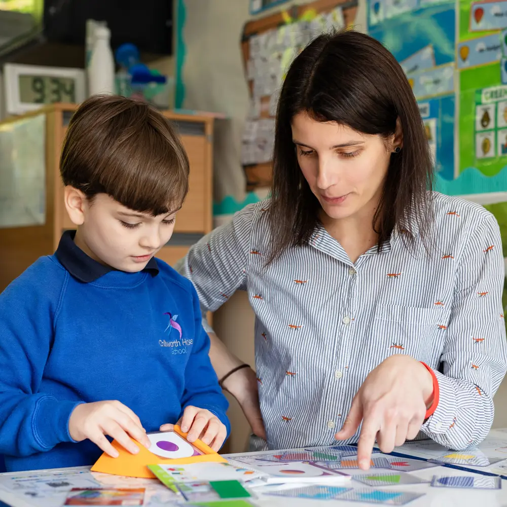 Young boy from Chilworth House School sat at a desk with teacher looking at shapes