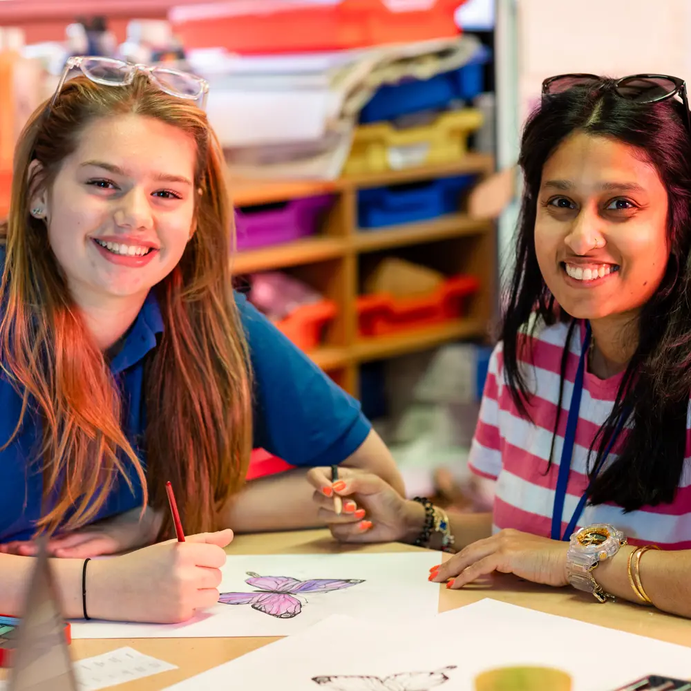 A young girl from Chilworth House Upper colouring with a member of staff