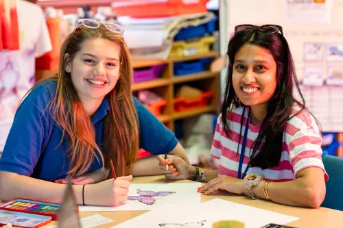A young girl from Chilworth House Upper colouring with a member of staff