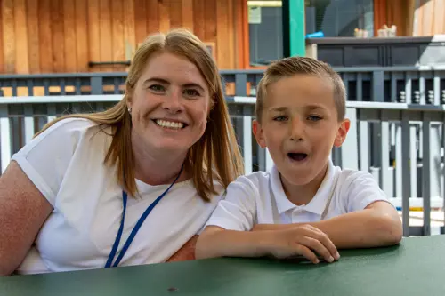 A young boy at Lakeside School sitting with a staff member looking at the camera
