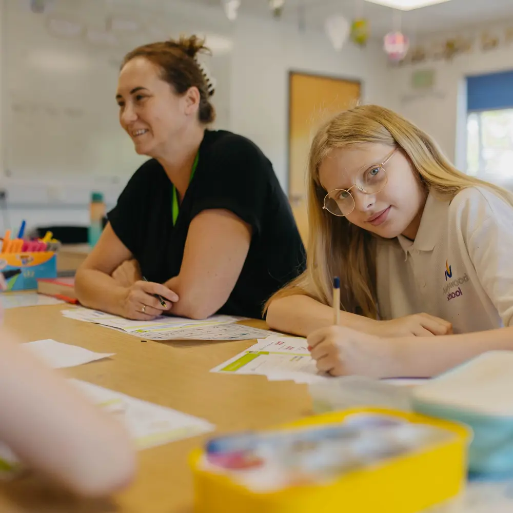 Blonde-haired girl sat at a table with a staff member at Abbeywood School
